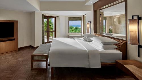 a bedroom with a large white bed and a bathroom at Grand Hyatt Bali in Nusa Dua