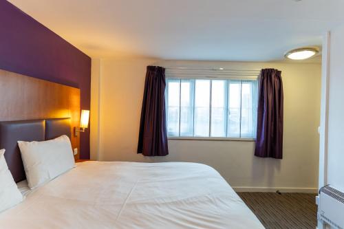a hotel room with a large bed and a window at Tyger Inn Derby in Derby