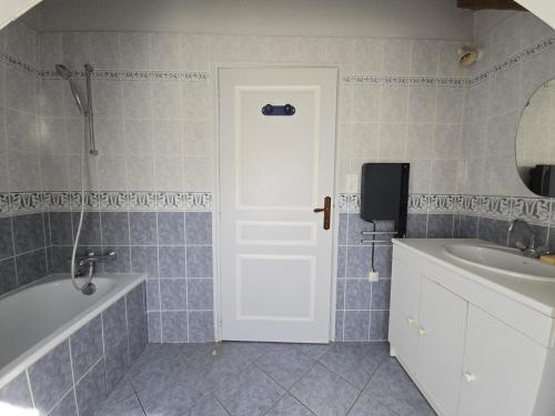 La salle de bains est pourvue d'une baignoire, d'un lavabo et d'une porte. dans l'établissement Maison de charme avec ruisseau, 5 chambres, proche Vallée de Dordogne et sites touristiques - FR-1-616-170, à Borrèze