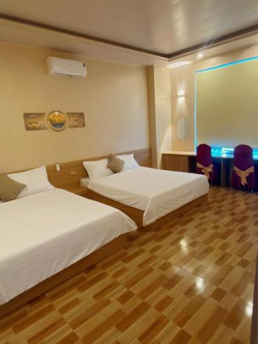 a hotel room with two beds and a table and chairs at thieuki 1 in Hà Tĩnh