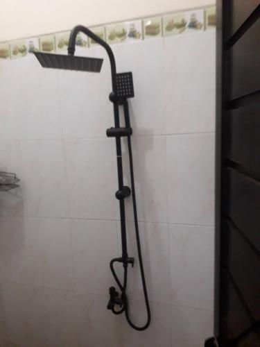 a shower with a shower head in a bathroom at Rama Shinta Guest House & Coffee in Timuran