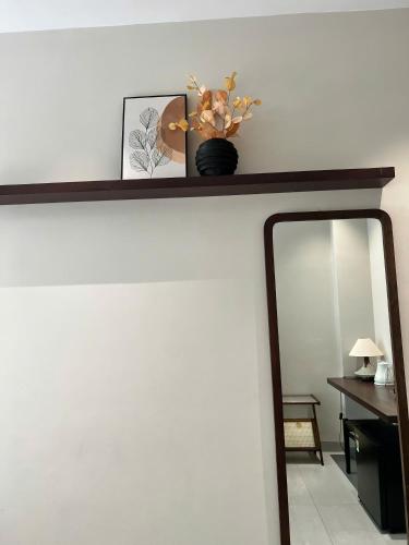 a mirror on a wall with a shelf and flowers at Ladyfit House in Thôn Trường Giang