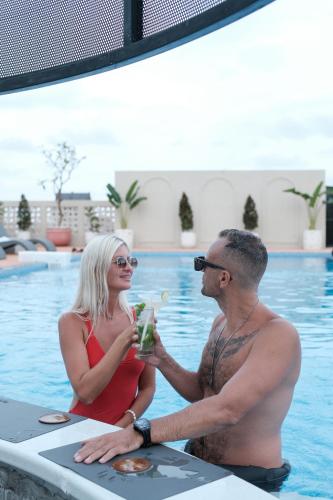a man and a woman sitting in the swimming pool at Aster Apartment Bali in Canggu