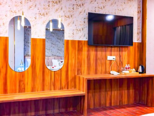 a room with three mirrors and a tv on a wall at Airport Hotel Bhadrapur in Bhadrapur Airport