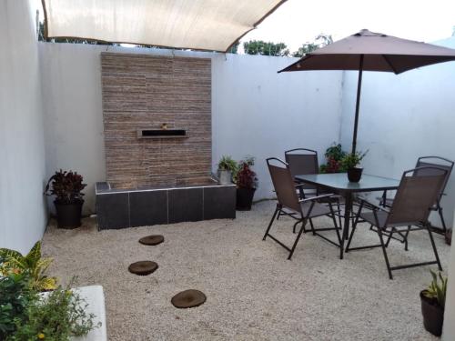 Un patio con una mesa y sillas y una sombrilla. en casa kiwi playa del carmen, en Playa del Carmen