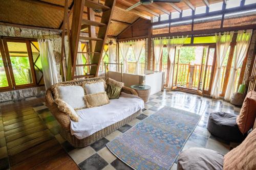 een woonkamer met een bank en een aantal ramen bij Unique Balian beach house in Antasari