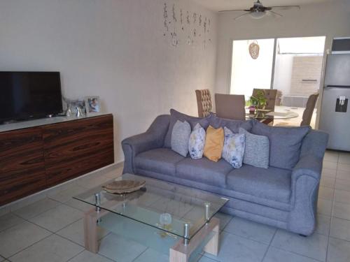 Una sala de estar con un sofá azul y una mesa. en casa kiwi playa del carmen, en Playa del Carmen
