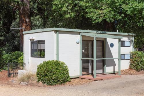 a small white shed with a green roof at Daylesford Holiday Park in Daylesford