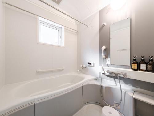 a white bathroom with a tub and a sink at Tabist THE GREEN OTARU in Otaru