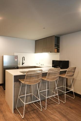 a kitchen with three bar stools and a counter at Aster Apartment Bali in Canggu