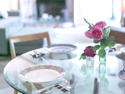a glass table with a plate and a vase of flowers at FOREAT akemanomori in Daisen