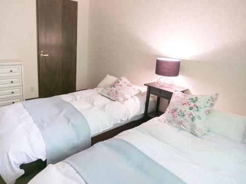 a bedroom with two beds and a lamp on a table at FOREAT akemanomori in Daisen