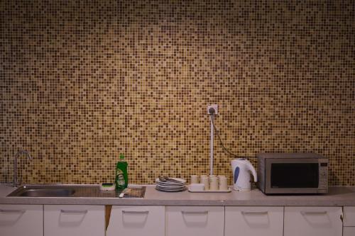 a kitchen counter with a sink and a microwave at Okay Marina Lumut Homestay in Lumut