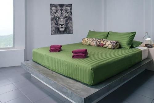 a green bed with pillows on a platform in a room at Villa on the Rocks in Koh Tao