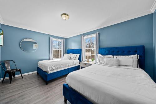 two beds in a room with blue walls at Spacious 6 BR Villa - Serene Scenic Mountain Escape in Bloomingburg