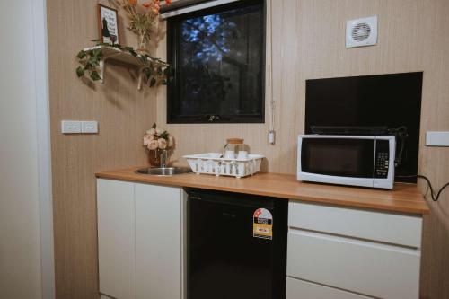cocina con encimera, microondas y fregadero en River Oasis Tiny House by Tiny Away, en Noojee