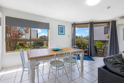 a dining room with a table and chairs and a couch at Kalua Holiday Apartments in Maroochydore