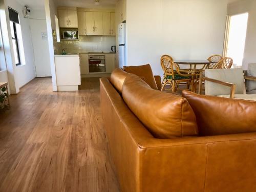 a living room with a brown couch and a kitchen at Kalua Holiday Apartments in Maroochydore