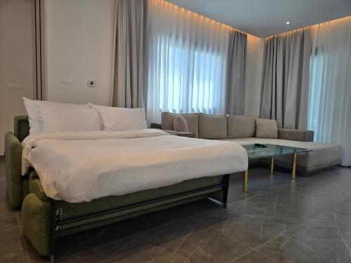 a bedroom with a bed and a couch and a table at TG NEW Luxury Private Resort & SPA Villas - Heated Salty Swimming Pool, Outdoor Jacuzzi, Sauna, Exotic Garden in Limassol