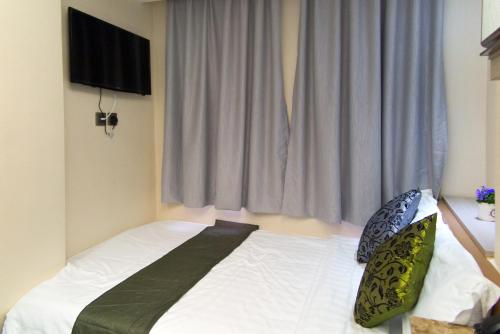 a bedroom with a bed with white sheets and a window at Metroplace Boutique in Hong Kong