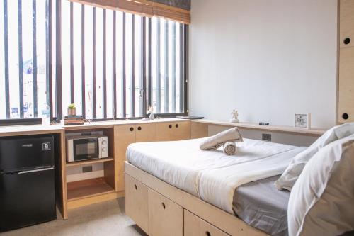 a bedroom with a bed and a microwave and windows at HomeBase Apartment Hotel in Manila