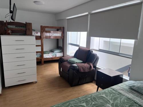 a bedroom with a bed and a chair and a dresser at Alquilo Departamento en Playa Pulpos in Lurín