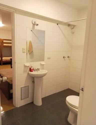 a white bathroom with a toilet and a sink at Alquilo Departamento en Playa Pulpos in Lurín
