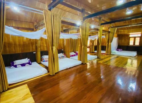 a room with four beds and a wooden floor at Homestay Dế Xu Phình in Co Ge Phong (1)