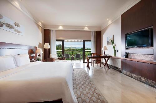 a hotel room with a large bed and a desk at Grand Metropark Villa Resort Sanya Yalong Bay - Beach shuttle and Singer performance in Sanya