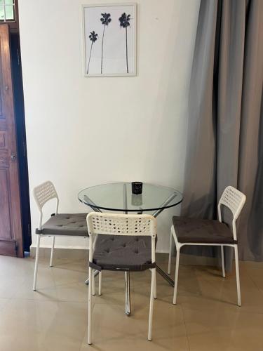 a glass table with two chairs and a glass table and two chairs at Peaceful studio home in South Goa in Salcete