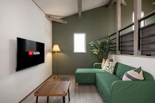 a living room with a green couch and a tv at Villa Gotemba Fuji in Gotemba