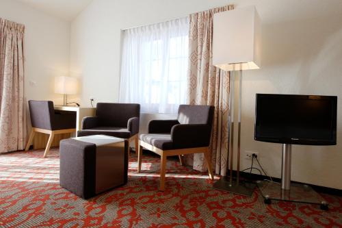 a hotel room with two chairs and a flat screen tv at Hotel Garni Testa Grigia in Zermatt