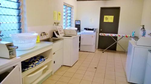 a kitchen with a sink and a washer and dryer at Island Leisure Resort in Nelly Bay