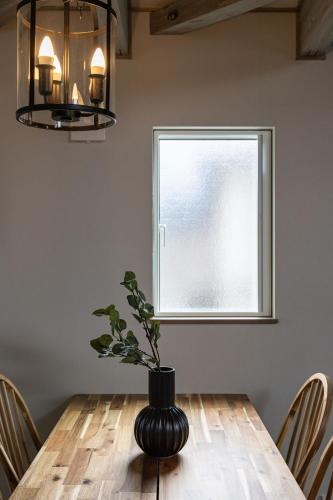 a dining room with a wooden table with a vase at Villa Gotemba Fuji in Gotemba