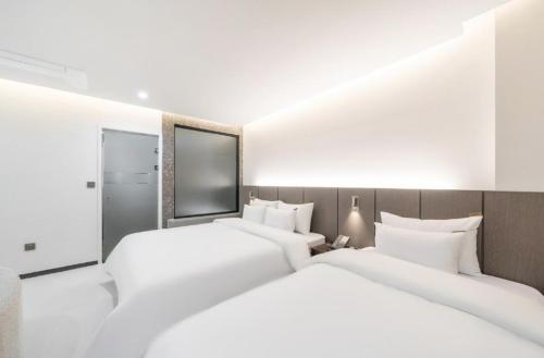 two beds in a hotel room with white sheets at Cheomdan Lantana Hotel in Gwangju