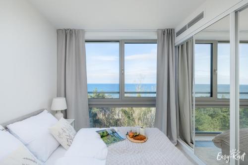 a bedroom with a bed with a view of the ocean at Prestige Pinea 613 - basen, sauna, jacuzzi w cenie pobytu - Easy - Rent Apartments in Pobierowo