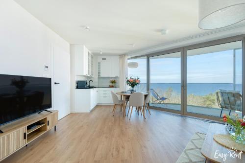 a living room with a large television and a table with chairs at Prestige Pinea 613 - basen, sauna, jacuzzi w cenie pobytu - Easy - Rent Apartments in Pobierowo