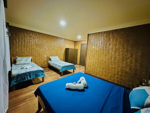 a room with two beds and a blue table at Lokal Hut Bed and Breakfast in Puerto Princesa City