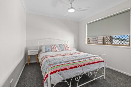 a white bedroom with a bed and a window at McNaughton Townhouse in Redcliffe