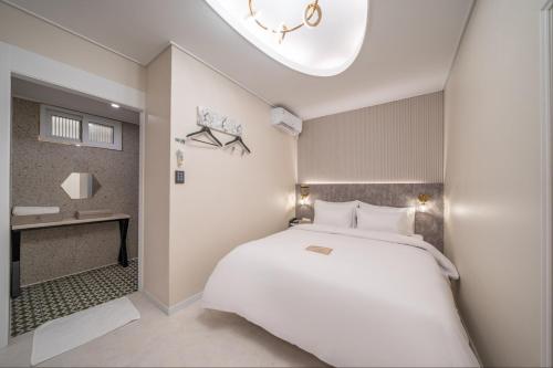 a bedroom with a large white bed and a bathroom at DK Airport Hotel in Incheon