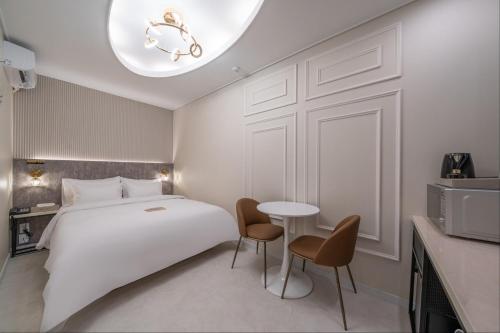 a bedroom with a white bed and a table and chairs at DK Airport Hotel in Incheon
