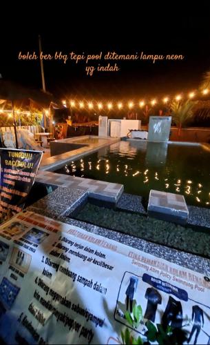 a view of a swimming pool at night with lights at Cassa Bonda Std Family Room in Machang