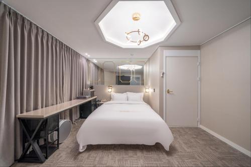 a bedroom with a large white bed and a desk at DK Airport Hotel in Incheon