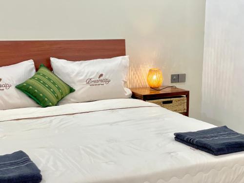 a bed with white sheets and green pillows at SKY VILLA - BKK Phnom Penh - Rooms & Apartments - FREE LAUNDRY in Phnom Penh