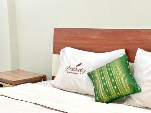 a bed with white sheets and a green pillow at SKY VILLA - BKK Phnom Penh - Rooms & Apartments - FREE LAUNDRY in Phnom Penh