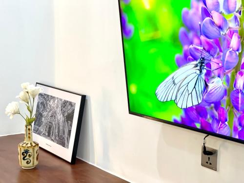 a vase of flowers and a picture of a butterfly at SKY VILLA - BKK Phnom Penh - Rooms & Apartments - FREE LAUNDRY in Phnom Penh