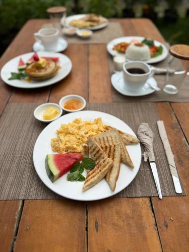 a wooden table with plates of breakfast food on it at Lokal Hut Bed and Breakfast in Puerto Princesa City