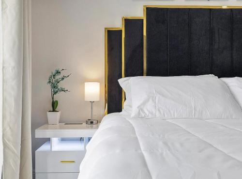 a white bed with a black headboard and a table with a lamp at Miami Oasis With Private Pool in Richmond West