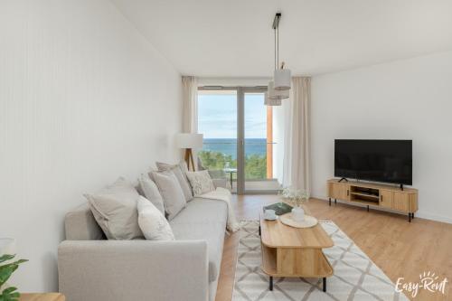 a white living room with a couch and a tv at Prestige Pinea 610 - basen, sauna, jacuzzi w cenie pobytu - Easy - Rent Apartments in Pobierowo