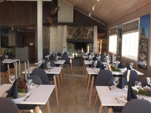 een restaurant met witte tafels en stoelen en een open haard bij Hovden Fjellstoge in Hovden